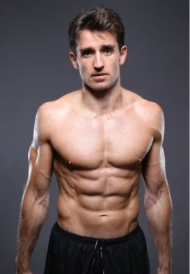 Muscular shirtless man with defined abs posing against a dark background, wearing black shorts.